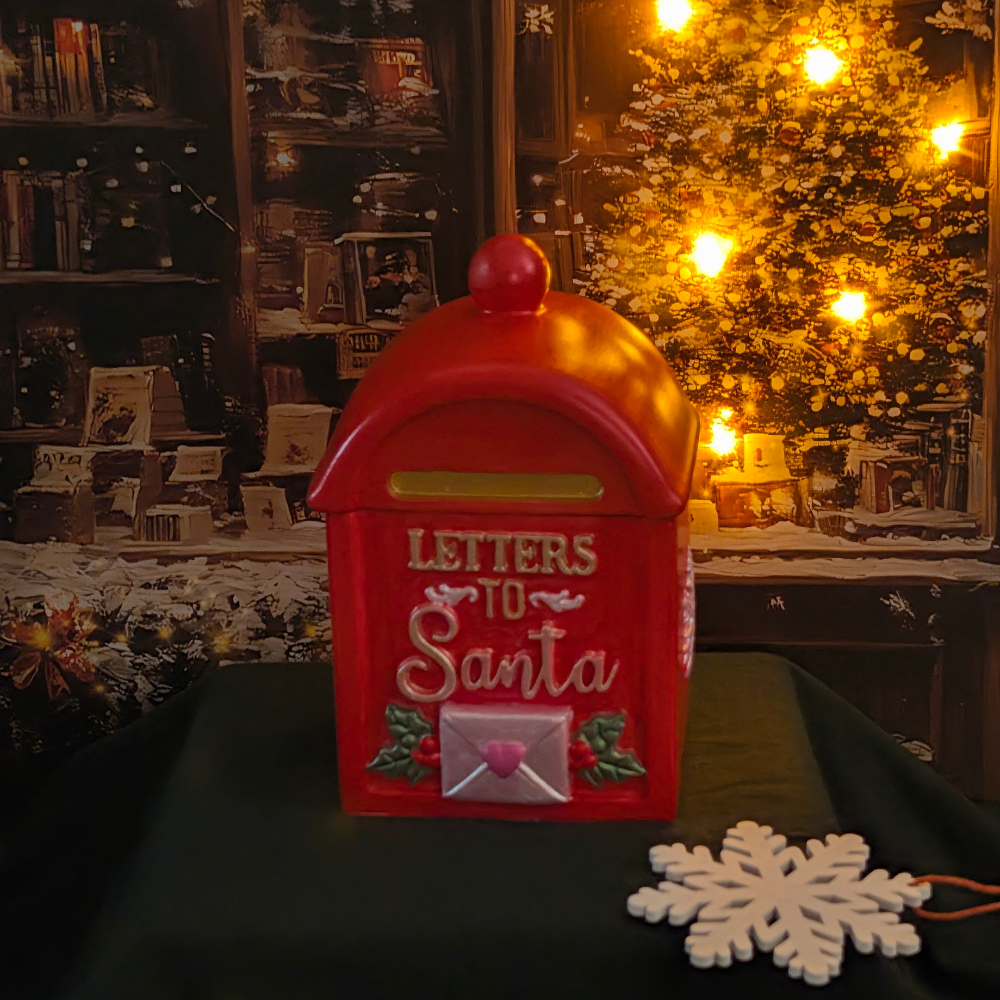 We have a red mail vessel with letters to Santa with a white envelope with a heart in the front The vessel are in top of green mantel and in the side a snowflake white and Christmas photo as a background with lights in the tree of the photo.