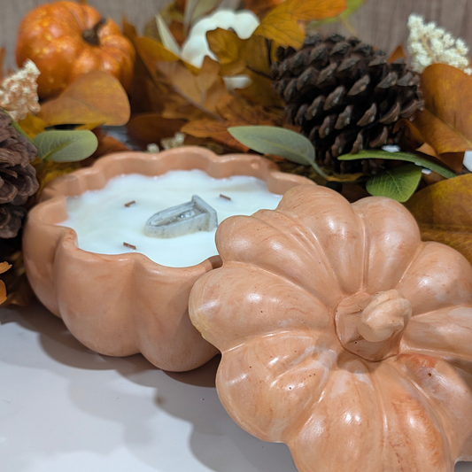 Handcrafted Lg Pumpkin Vessel in orange inside of the vessel is fill with coconut apricot wax in front of fall decoration leaves,  pine corn