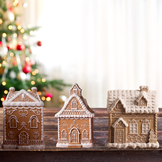 We have 3 gingerbread vessels houses the color is brown and white. The white is simulating snow in top of wood countertop in front of a Christmas tree as a background
