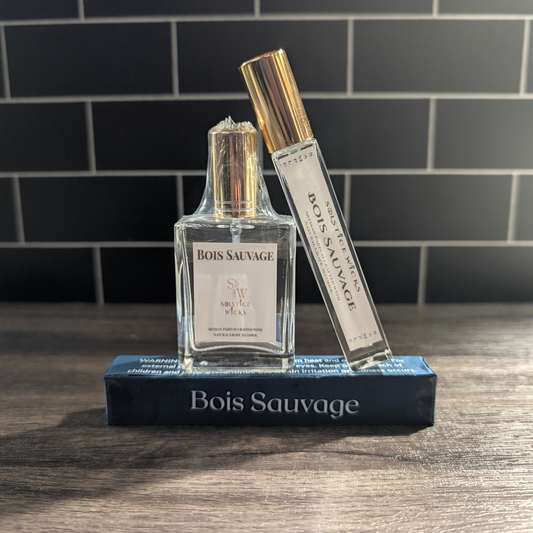 A bottle of Bois Sauvage cologne and a matching To-Go spray stand on top of a dark blue box on a wooden surface, with a dark tiled background.