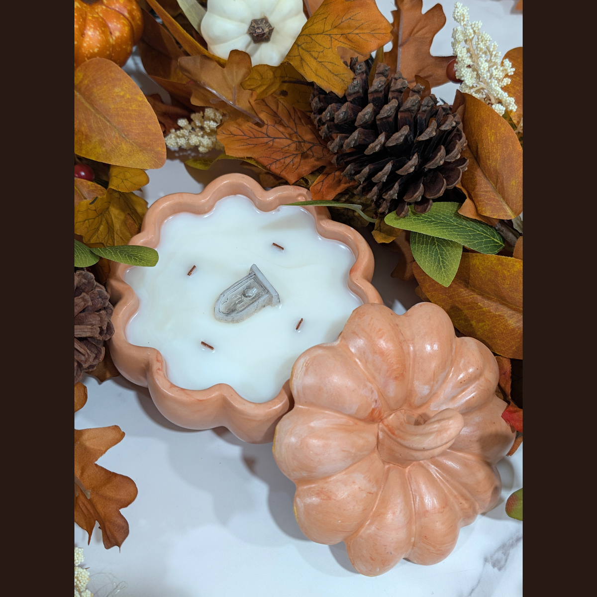the photo is take it from the top of the Handcrafted Lg Pumpkin Vessel in orange inside of the vessel is fill with coconut apricot wax in front of fall decoration leaves,  pine corn