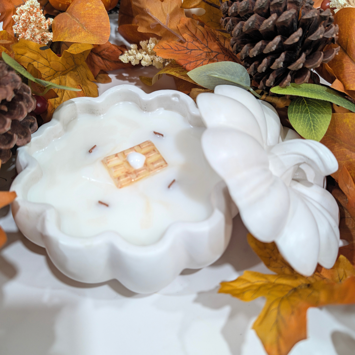 We have a handcrafted White large pumpkin in front of a falls decoration like leaves, pine corn. white flower, but this time the pumpkin is open and inside is fill with coconut apricot wax and a waffle decoration with whipped crem on the waffle
