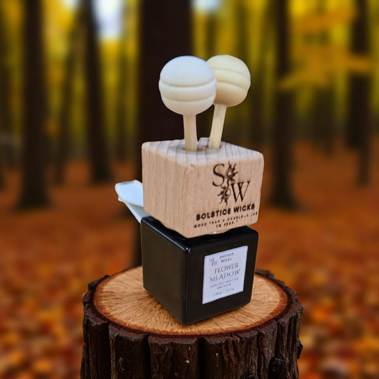 Vent Clip Air car diffuser labeled “Flower Meadow” with wooden cap and rope, surrounded by geranium, lavender, and chamomile — floral essential oil scent for car aromatherapy.